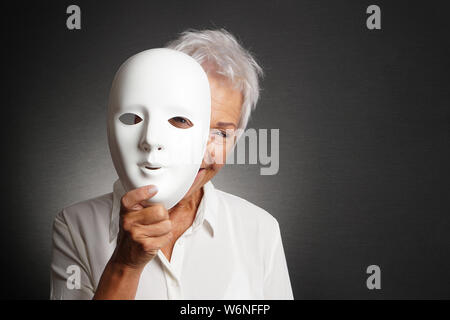 happy smiling laughing senior woman peeking from behind mask Stock Photo