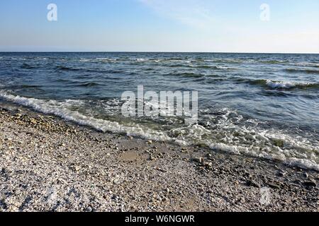 Wavy seascape view from the beach with pebbles and seashells on it. Stock Photo
