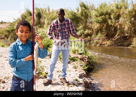 Portrait of afro fisherman holding fishing rod with fish on hook Stock  Photo - Alamy