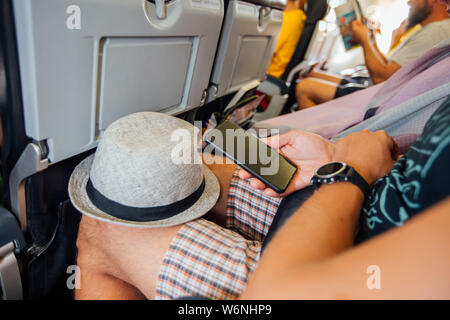 Man using a smartphone in an aircraft. Stock Photo