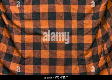 Fabric with black and orange cages pattern. Plaid material. Crumpled Cloth Blank Background Stock Photo