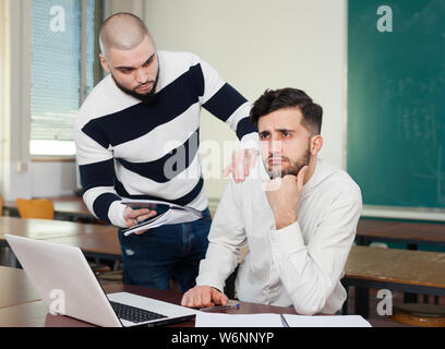 Young guy sitting at classroom worried because of difficulties with studies Stock Photo