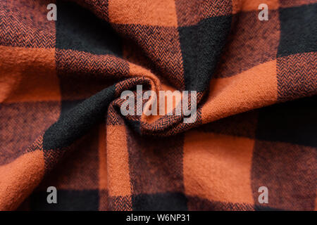 Wrinkled black and orange cell clothes background. Fabric with black red cages pattern. Plaid material. Crumpled Cloth Blank Background Stock Photo