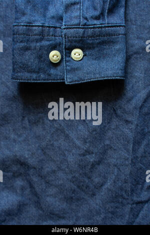 Blue denim shirt cuff with white buttons close-up. Garment background Stock Photo