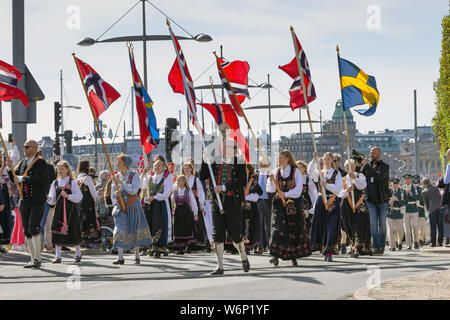 Norwegian patriots holding national flags and parade crowd in during Norways' independence day celebration events in Ostermalmstorg, suburb, Sweden Stock Photo