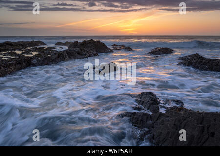 Westward Ho! seascape sunset with waves crashing around the rocks Stock Photo