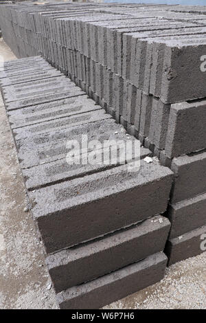 Handmade bricks made of black volcanic sand, water and cement. Manual production on Bali island, Indonesia. The process of sun-drying Stock Photo