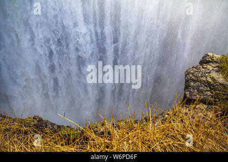 Dramatic close-up of water tumbling over Victoria Falls from the Zambian side.  The air is thick with spray and coats the vegetation in the foreground Stock Photo