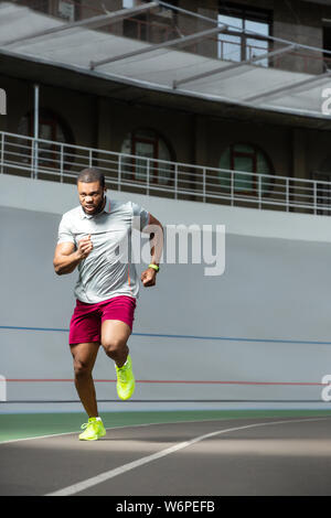 Sportive energetic African American young man running outdoors Stock Photo