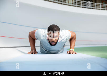 Determined athletic man doing push-ups at the stadium Stock Photo