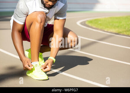 Serious bearded African American athletic man tying laces Stock Photo