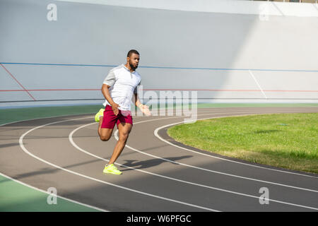 Strong purposeful sportive man on the running track Stock Photo