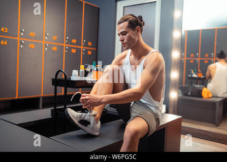 Handsome young man lacing his sports shoes Stock Photo