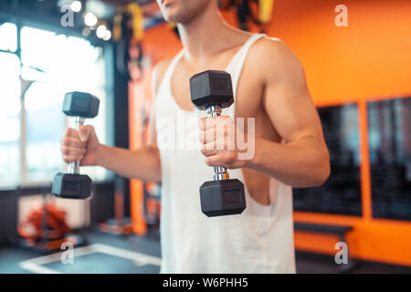 Selective focus of a dumbbell in male hands Stock Photo