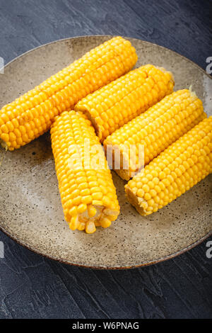 Tasty boiled corn cobs with butter and salt on plate Stock Photo