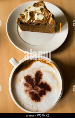 Coffee and cake in a National Trust cafe at a stately home / house. The the cappuccino coffee has the National Trust Oakleaf trademark logo in sprinkled chocolate. UK (110) Stock Photo