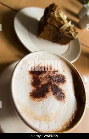 Coffee and cake in a National Trust cafe at a stately home / house. The the cappuccino coffee has the National Trust Oakleaf trademark logo in sprinkled chocolate. UK (110) Stock Photo