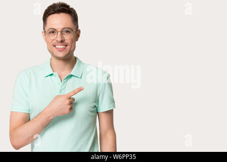 Young man in glasses looking at camera pointing finger aside Stock Photo