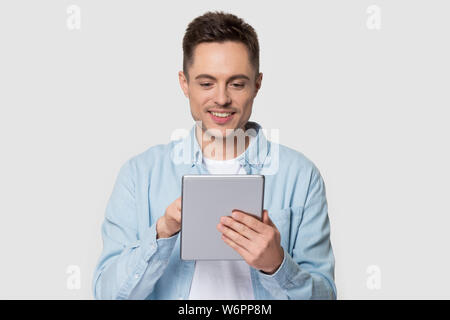 Smiling young man using modern tablet standing on grey background Stock Photo