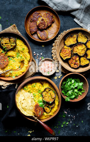Bengali Khichdi - Lentil, Millet Soup - a Gluten-free Vegan meal served with sauteed eggplant, poppy seeds fritters, and papadum. Stock Photo