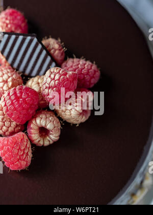 Chocolate truffle cake with raspberries and chocolate decoration on top.