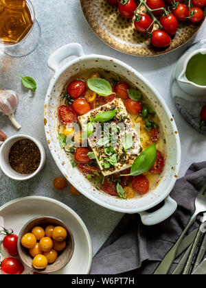 Baked feta cheese with cherry tomatoes and herbs Stock Photo