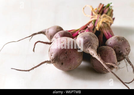 Bundle of young organic garden beetroot over white marble background. Stock Photo