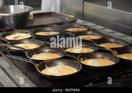 Eggs for airline meals frying on pans in large-scale commercial kitchen Stock Photo