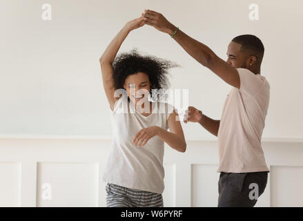 Happy young african couple holding hands dancing laughing at home Stock Photo