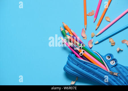 Funny Back to School concept - pencil case eating pencils on blue background. Space for text.. Space for text. Flat lay Stock Photo