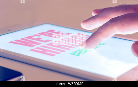 replying to an announcement of new job hires through the internet with a tablet. Job search and job opportunities Stock Photo