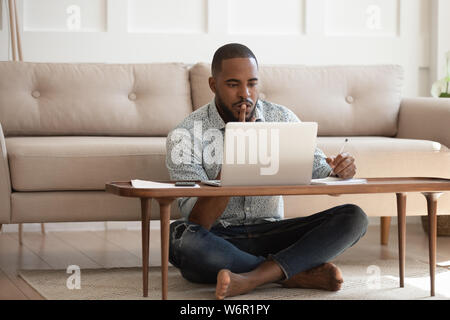 Focused african man studying or working on laptop at home Stock Photo