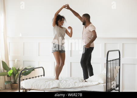 Young romantic african american couple wearing pajamas dancing on bed Stock Photo