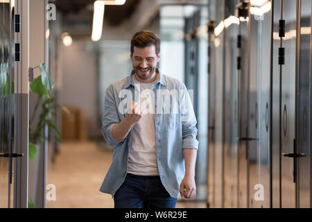 Happy euphoric young business man celebrating professional victory in office Stock Photo
