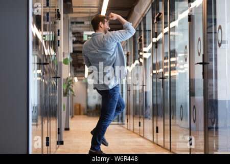 Overjoyed funny young business man jumping in hallway celebrating victory Stock Photo