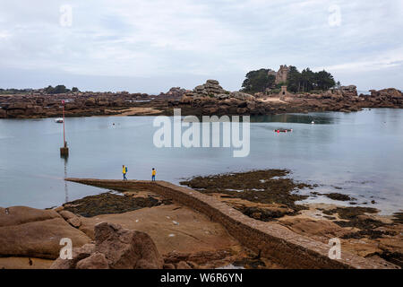 France, Brittany, Cotes d'Armor, mother and son walking on pier at the Pink granit coastline at the Men Ruz lighthouse at Ploumanach Stock Photo