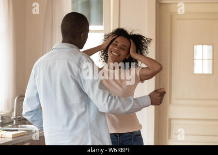Cheerful active african couple dancing in kitchen Stock Photo