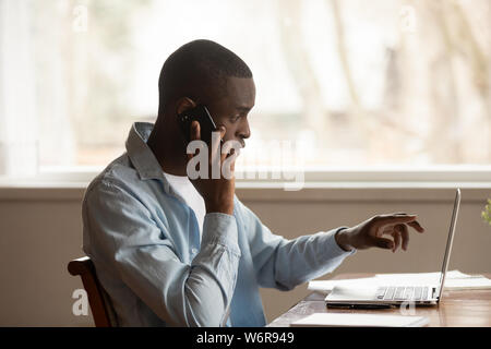 African guy looking at computer screen talk on phone Stock Photo