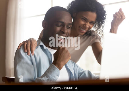 African couple look at computer feels excited celebrating lottery win Stock Photo