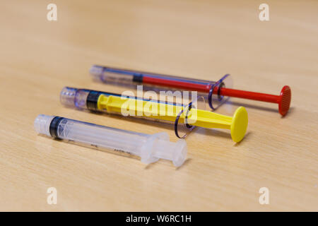 Three small medical syringes of different size and colors Stock Photo