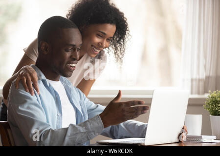 African spouses look at computer screen having fun at home Stock Photo
