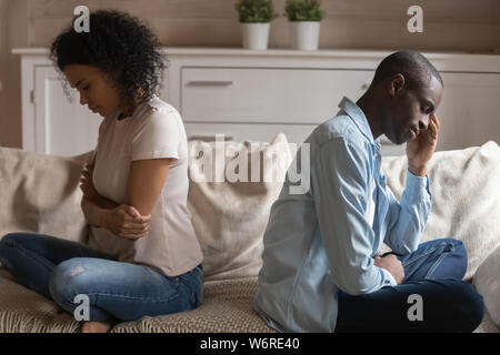 Unhappy african couple ignoring each other sitting separately on couch Stock Photo