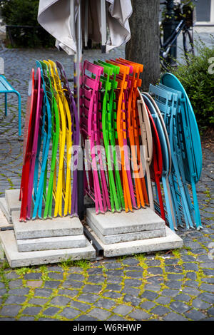 Colourful restaurant chairs, in a beer garden, folded together, Stock Photo