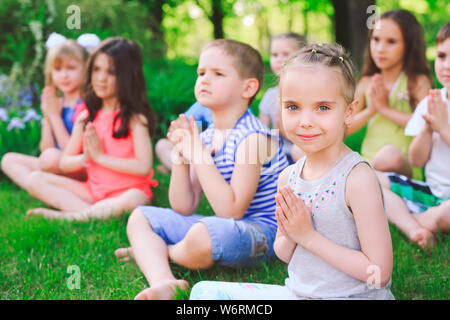 A large group of children engaged in yoga in the Park sitting on the grass Stock Photo