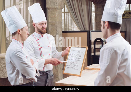 Head Chef and his staff in kitchen. interacting to in commercial kitchen Stock Photo