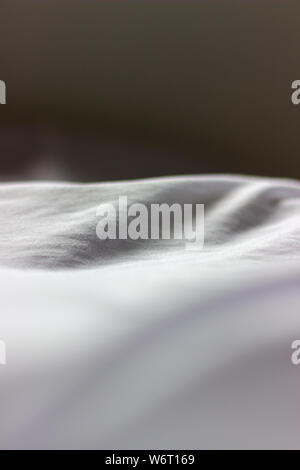 Folds in white cloth close up in shallow depth of field Stock Photo