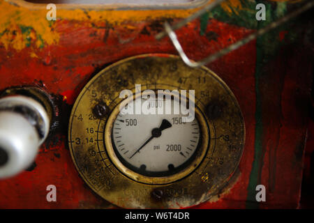 Details of a steampunk like old, dirty, colorful and rusty PSI manometer on an industrial heavy iron machinery Stock Photo