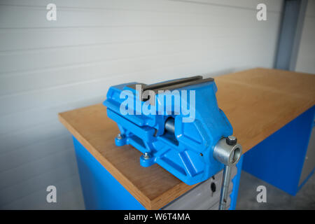 Shallow depth of field image with a heavy iron vice on a workbench inside a workshop with no people around Stock Photo