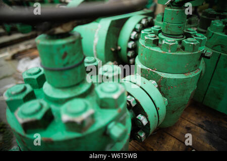 Shallow depth of field image with worn out heavy iron industrial equipment used in the oil and gas drilling industry (rusty bolts, nuts, pipes, levers Stock Photo