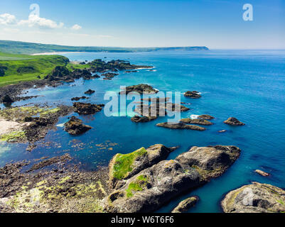 Vivid emerald-green water at Ballintoy harbour along the Causeway Coast in County Antrim. Rugged coastal landscape of Northern Ireland. Stock Photo
